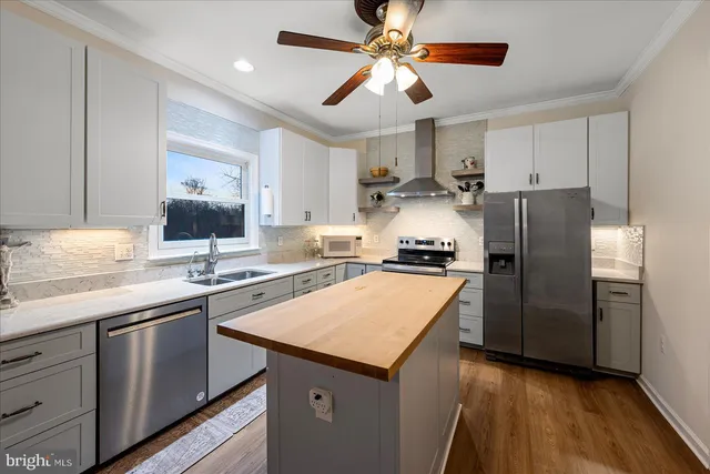 a kitchen with stainless steel appliances granite countertop a sink a stove a refrigerator cabinets and wooden floor