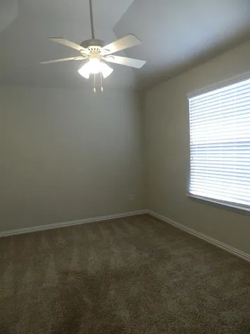 an empty room with a window and a fan