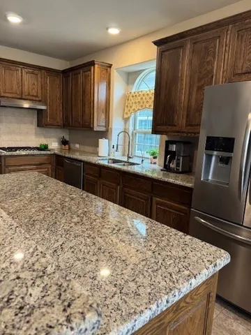 a kitchen with stainless steel appliances granite countertop wooden cabinets a stove top oven a sink and dishwasher