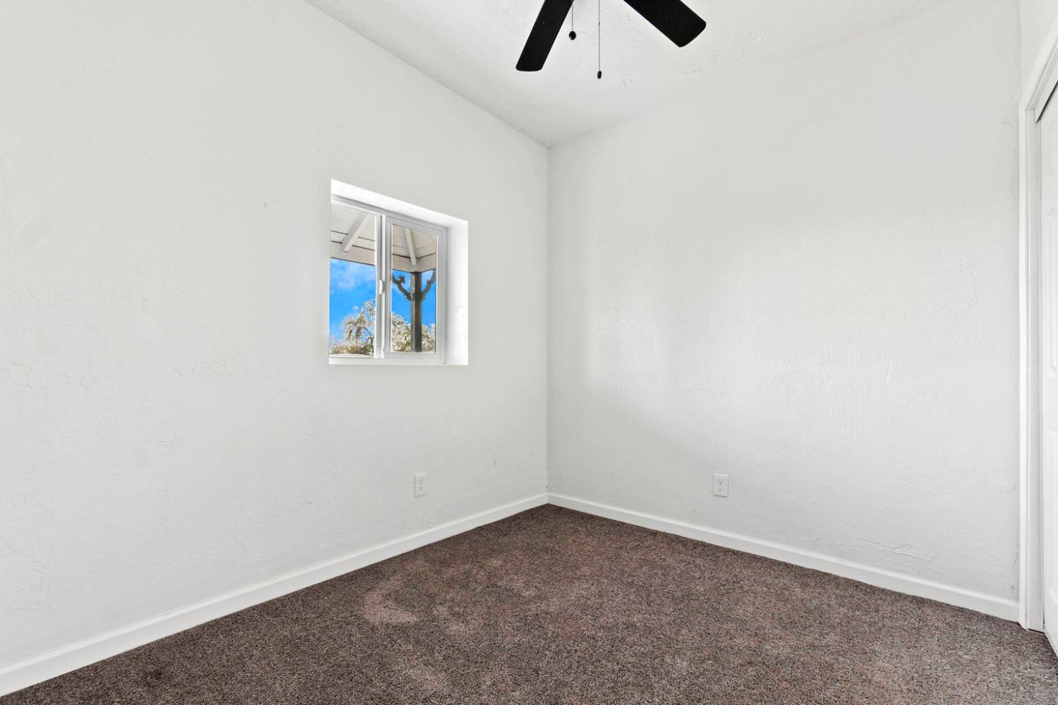 124 East 4th Street Hanford, CA 93230 - Photo 14 of 23 an empty room with ceiling fan and window