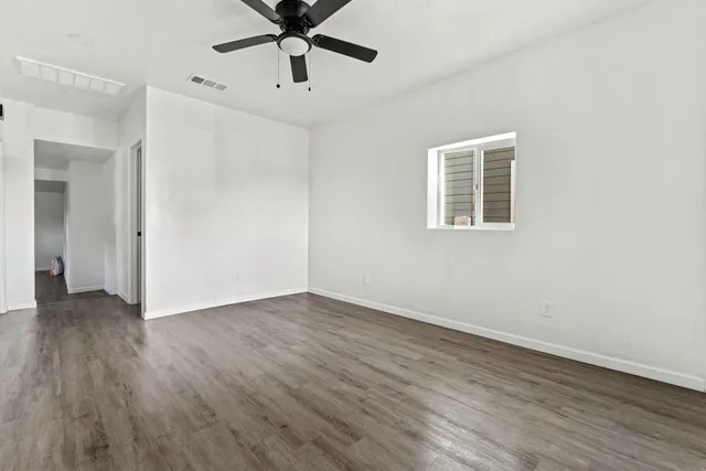 an empty room with wooden floor and windows