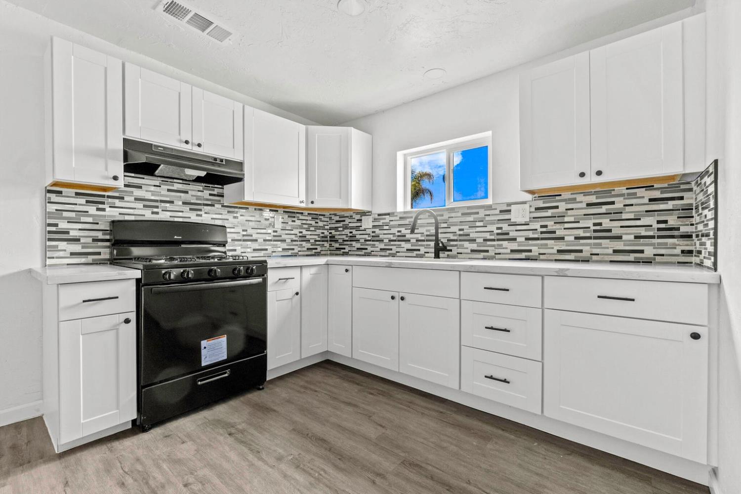 124 East 4th Street Hanford, CA 93230 - Photo 9 of 23 a kitchen with granite countertop white cabinets and stainless steel appliances