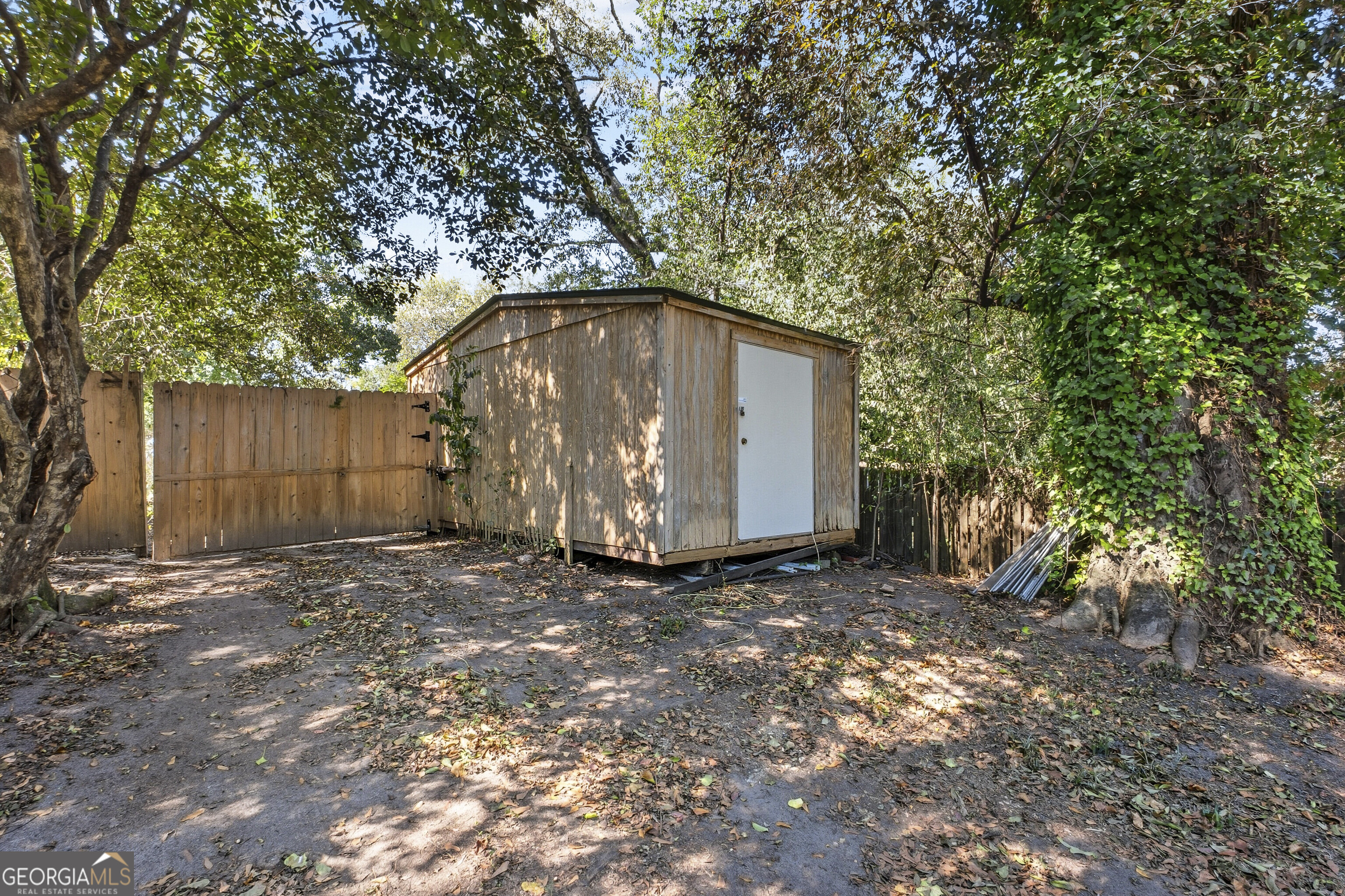 216 Hines Terrace Macon, GA 31204 - Photo 48 of 52 a backyard of a house with large trees and a wooden fence