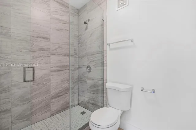 a white toilet sitting next to a shower