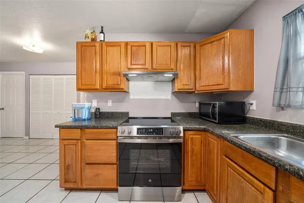 a kitchen with granite countertop a sink stove and cabinets
