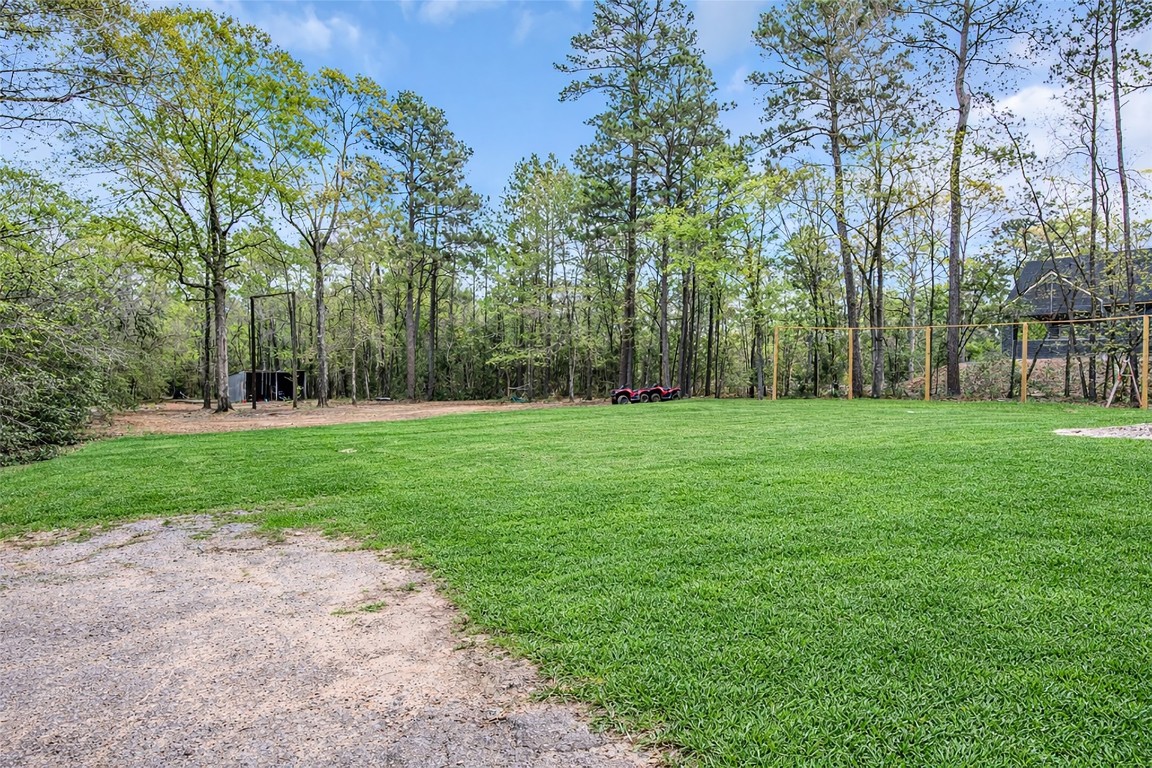 10040 Shepard Hill Road Willis, TX 77318 - Photo 11 of 36 This photo showcases a spacious backyard with a lush green lawn bordered by tall trees, offering a serene and private outdoor space. Ideal for families and gatherings.