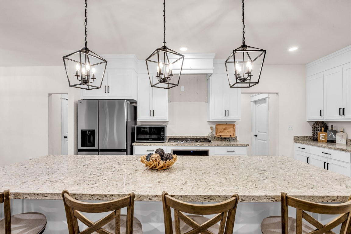 10040 Shepard Hill Road Willis, TX 77318 - Photo 20 of 36 This kitchen features a spacious island with granite countertops, elegant pendant lighting, and stainless steel appliances. White cabinetry and ample storage offer a clean, modern look, while the open layout provides a welcoming space for entertaining.
