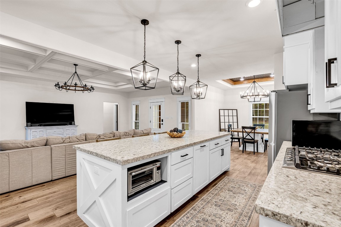 10040 Shepard Hill Road Willis, TX 77318 - Photo 21 of 36 This spacious open-concept living area features a modern kitchen with a large granite island, stylish pendant lighting, and stainless steel appliances. It seamlessly connects to a cozy living room with a sectional sofa and flat-screen TV, and a dining area with ample natural light.