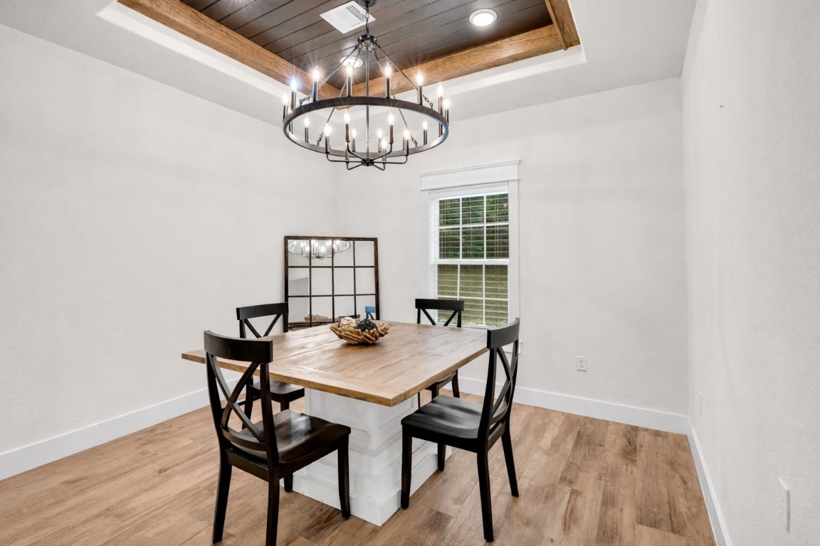 10040 Shepard Hill Road Willis, TX 77318 - Photo 24 of 36 This dining room features a stylish wooden table with four chairs, a large window for natural light, and a rustic chandelier. The wood-paneled ceiling adds warmth, while the light walls and flooring provide a modern touch.