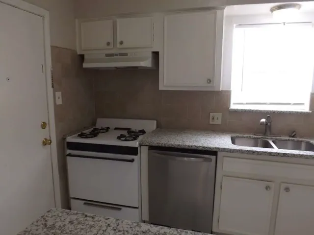 a kitchen with granite countertop a sink stove and refrigerator
