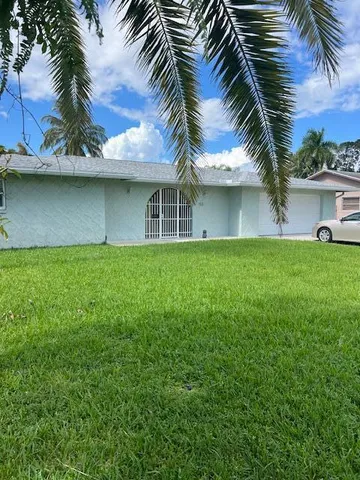 a backyard of a house with plants and palm tree