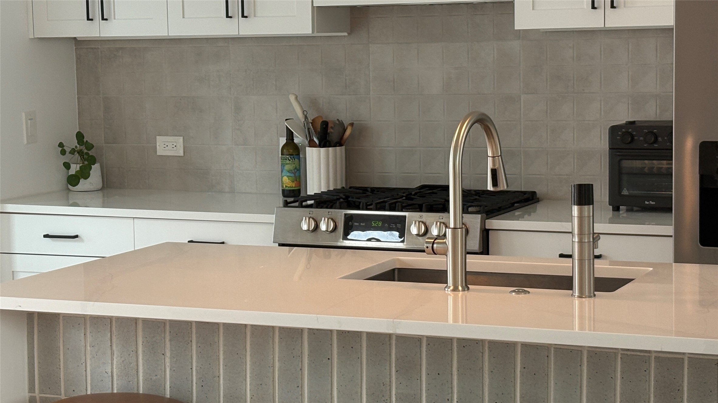 1816 Adina Street, Unit 2 Austin, TX 78721 - Photo 8 of 25 Kitchen island featuring a single-basin sink with a gooseneck faucet, light-toned countertop, and vertical tile facade