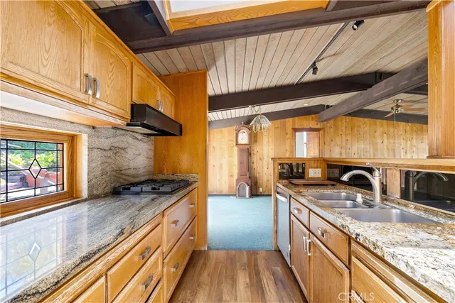 a kitchen with stainless steel appliances granite countertop a sink a stove and a wooden cabinets