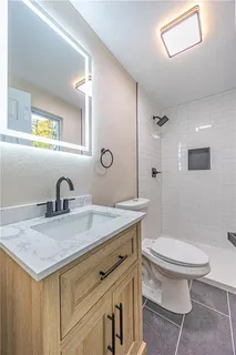 a bathroom with a granite countertop toilet sink and mirror