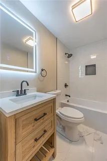 a bathroom with a granite countertop sink toilet a large mirror a bathtub and shower