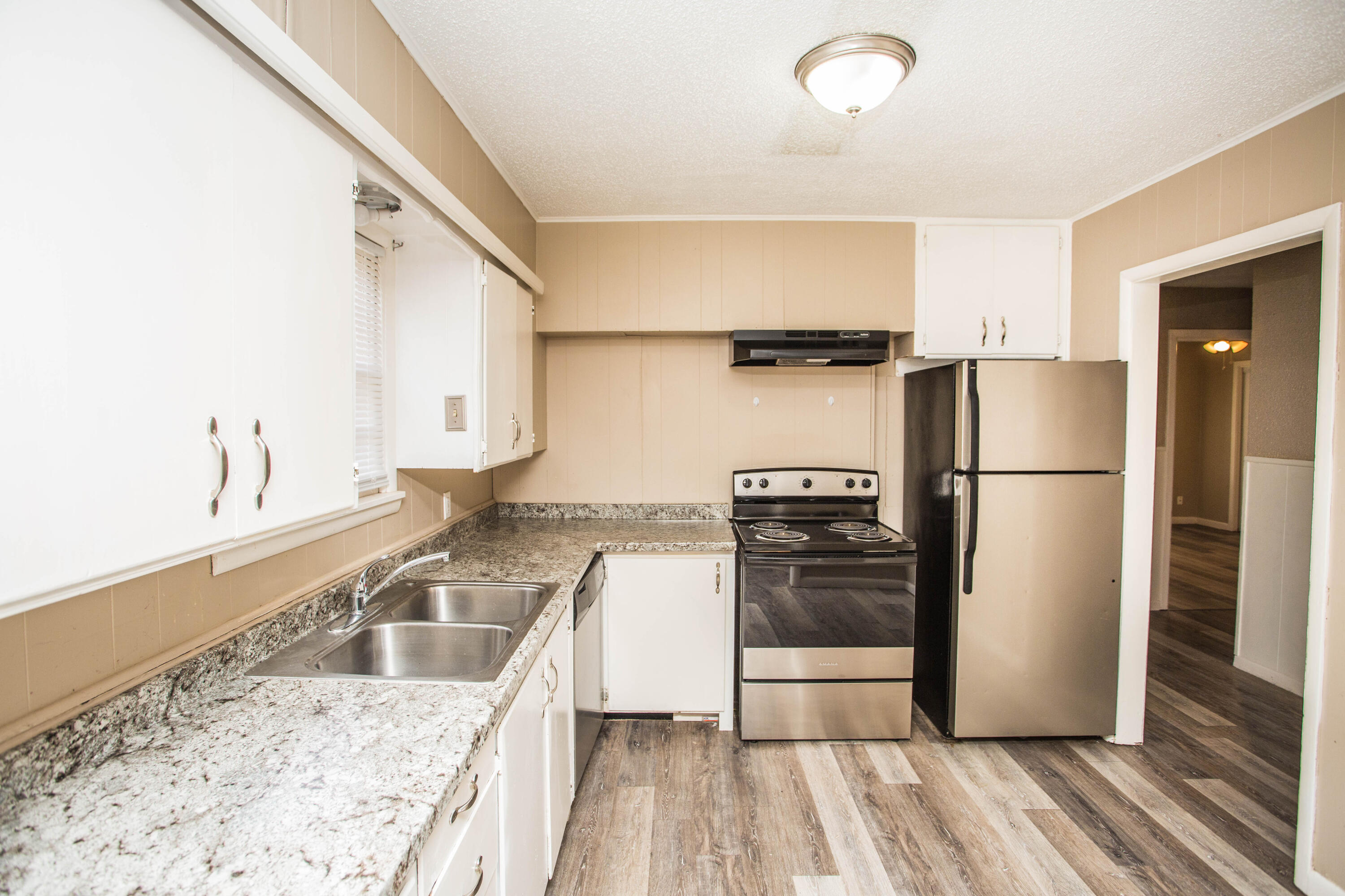 4309 42nd Street Lubbock, TX 79413 - Photo 7 of 25 a kitchen with granite countertop a refrigerator and a sink