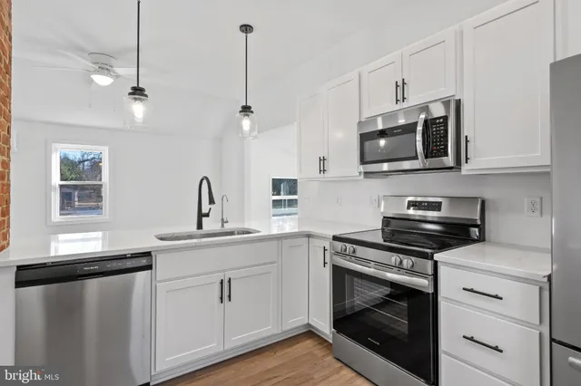 a kitchen with white cabinets stainless steel appliances and sink