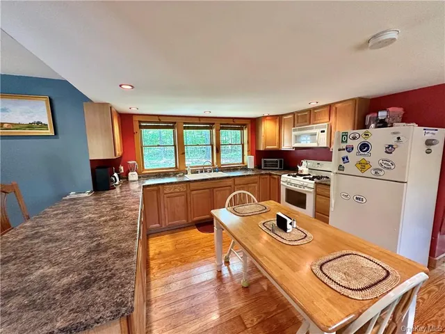 a kitchen with a refrigerator a stove a sink dishwasher and wooden cabinets with wooden floor