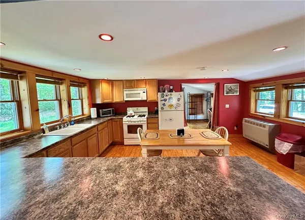 a large kitchen with stainless steel appliances granite countertop a large window and a living room view