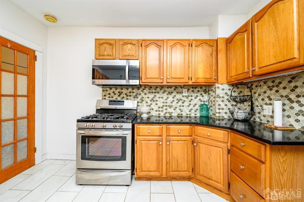 47 Marion Street Port Reading, NJ 07064 - Photo 37 of 57 a kitchen with stainless steel appliances granite countertop a stove a sink and a microwave oven in a white refrigerator