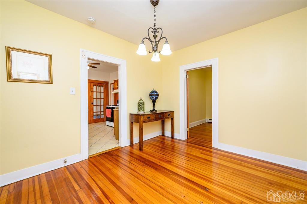 47 Marion Street Port Reading, NJ 07064 - Photo 10 of 57 a dining room with wooden floor a chandelier a wooden table and chairs