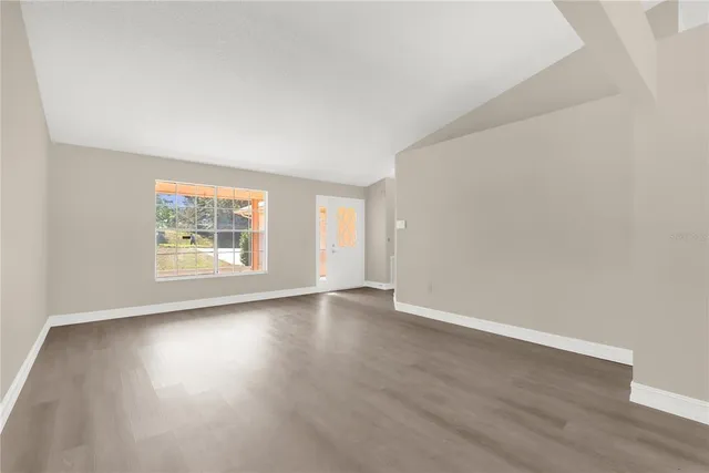 an empty room with wooden floor and windows