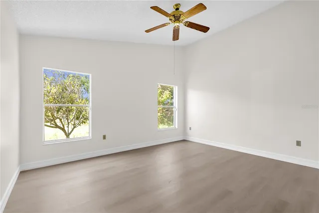 an empty room with windows and fan