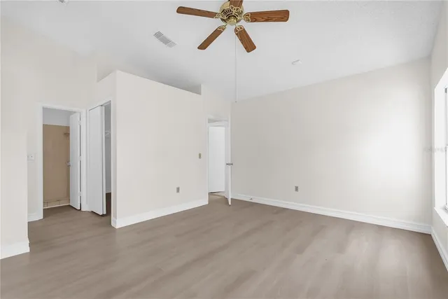 an empty room with wooden floor and windows