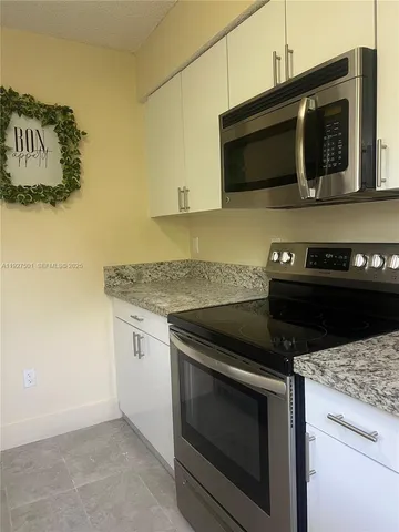 a kitchen with granite countertop stainless steel appliances a stove a microwave and cabinets