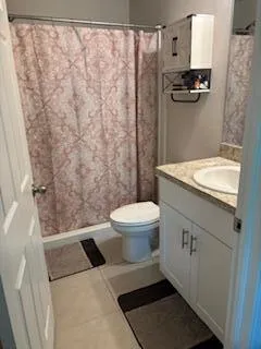 a bathroom with a granite countertop toilet a sink and a shower