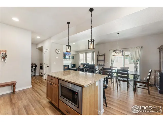 a open kitchen with stainless steel appliances granite countertop a stove top oven a dining table and chairs with wooden floor