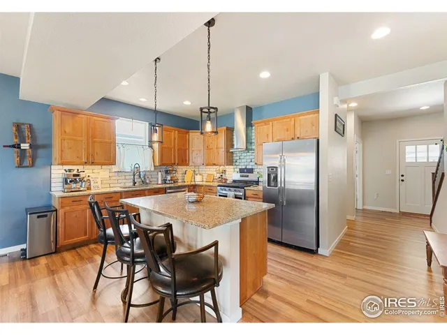 a kitchen with stainless steel appliances kitchen island granite countertop a refrigerator a stove a sink with a dining table and chairs