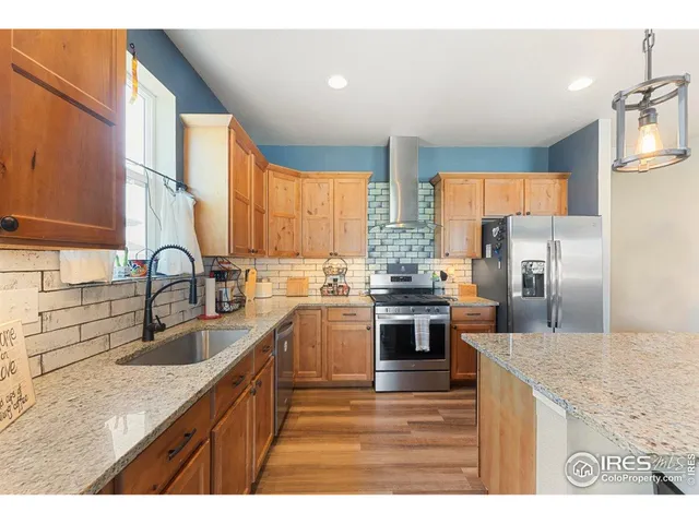 a kitchen with stainless steel appliances granite countertop a sink a stove and refrigerator