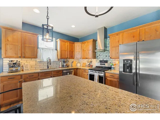 a kitchen with stainless steel appliances granite countertop a refrigerator a sink dishwasher a stove and white cabinets with wooden floor