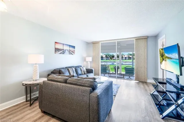 a living room with furniture a flat screen tv and a floor to ceiling window