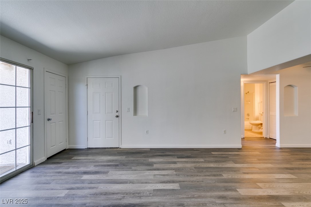 3318 North Decatur Boulevard, Unit 2138 Las Vegas, NV 89130 - Photo 13 of 40 Empty room featuring baseboards, healthy amount of natural light, wood finished floors, and lofted ceiling