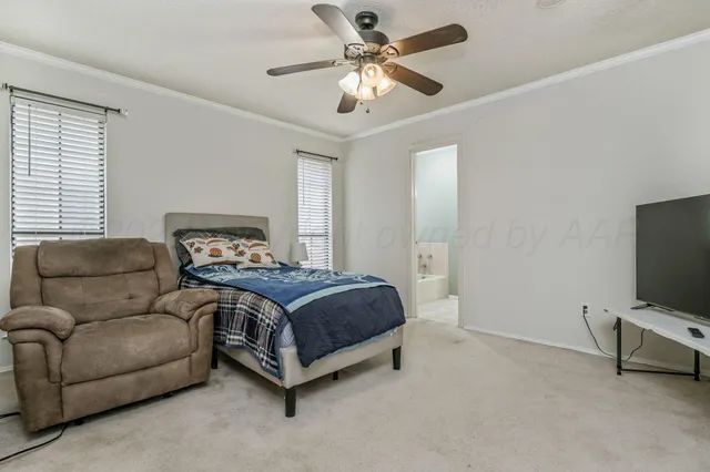 a spacious bedroom with a bed and a flat screen tv