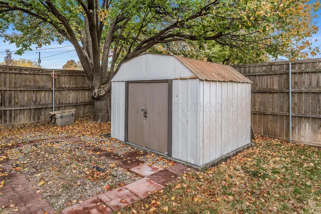 a backyard of a house with large trees and wooden fence