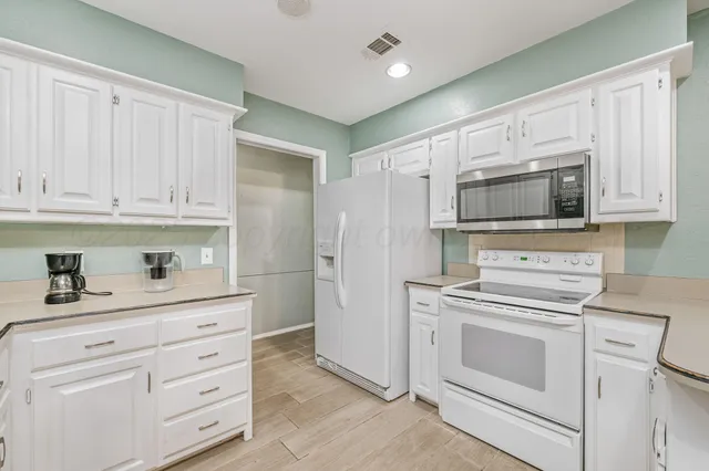 a kitchen with white cabinets and white appliances