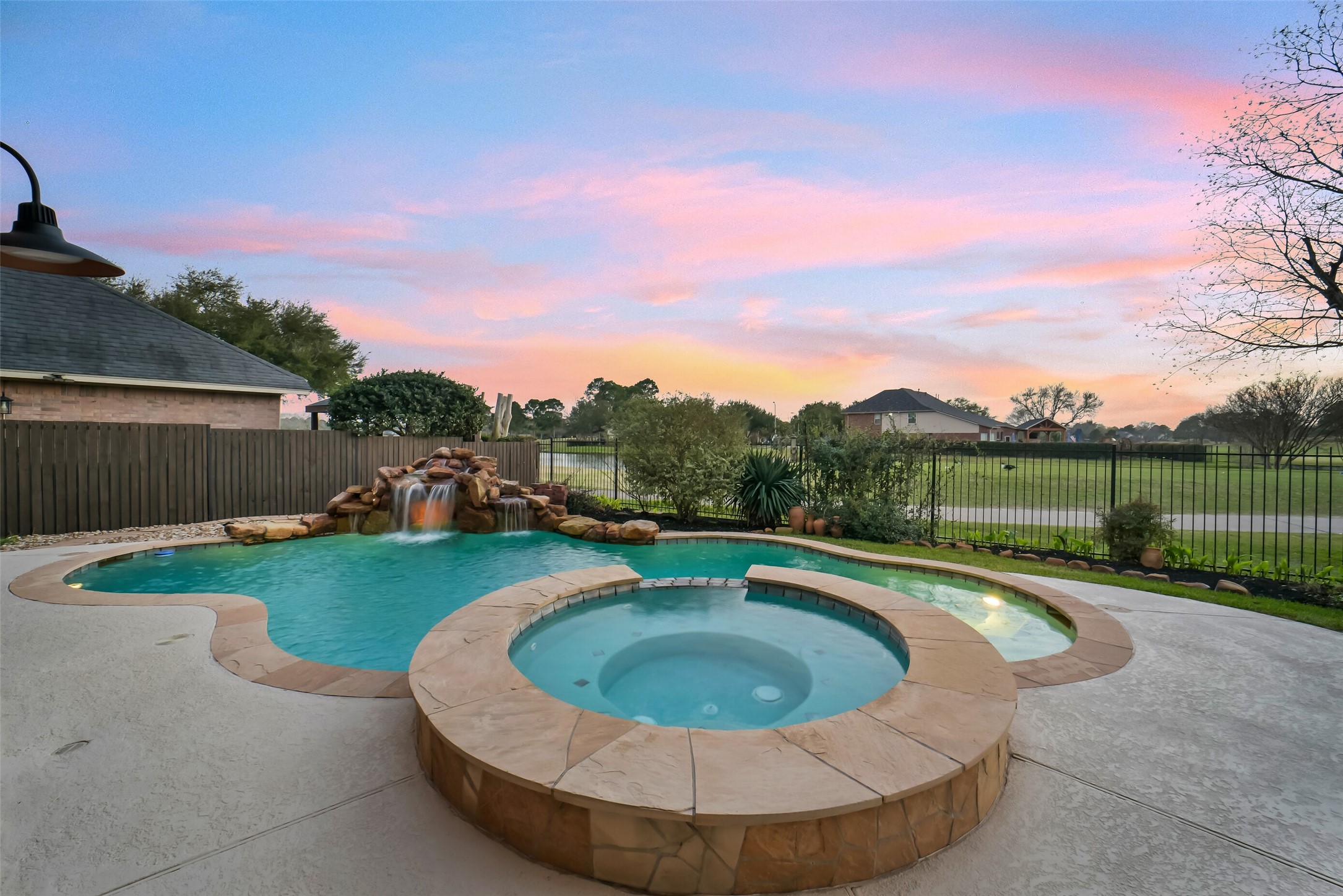 24403 Falcon Point Drive Katy, TX 77494 - Photo 3 of 32 Breathtaking backyard oasis featuring a sparkling pool and spa with a waterfall grotto, perfect for outdoor entertaining or quiet relaxation.