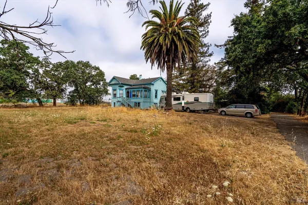 a front view of a house with garden and trees