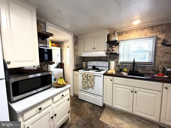 a kitchen with granite countertop white cabinets and white appliances