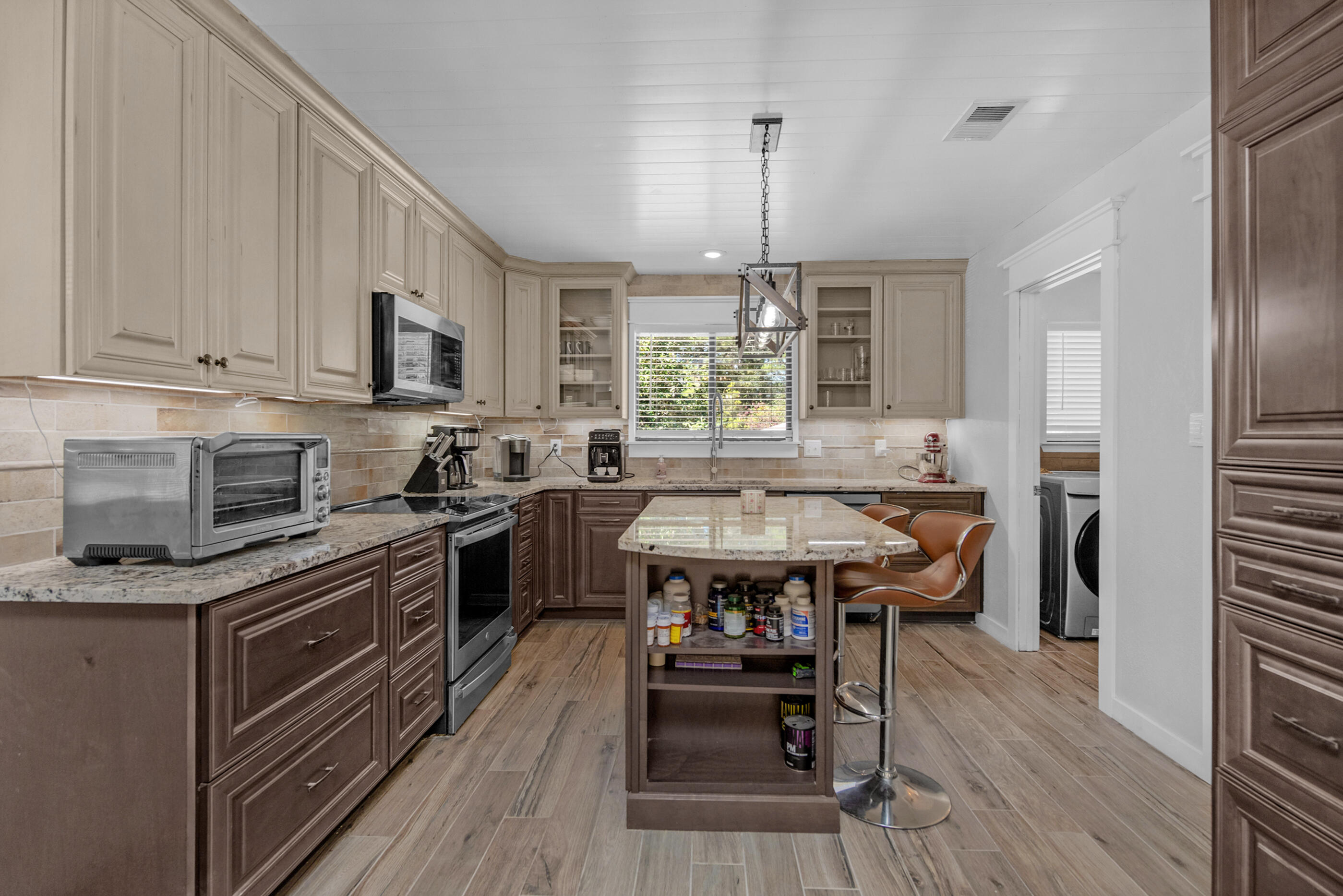 6539 Robar Tesora Street Navarre, FL 32566 - Photo 14 of 48 a kitchen with stainless steel appliances granite countertop a stove top oven a sink dishwasher and a refrigerator with wooden floor