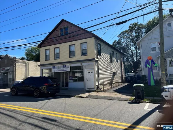 a front view of a house with cars parked on road