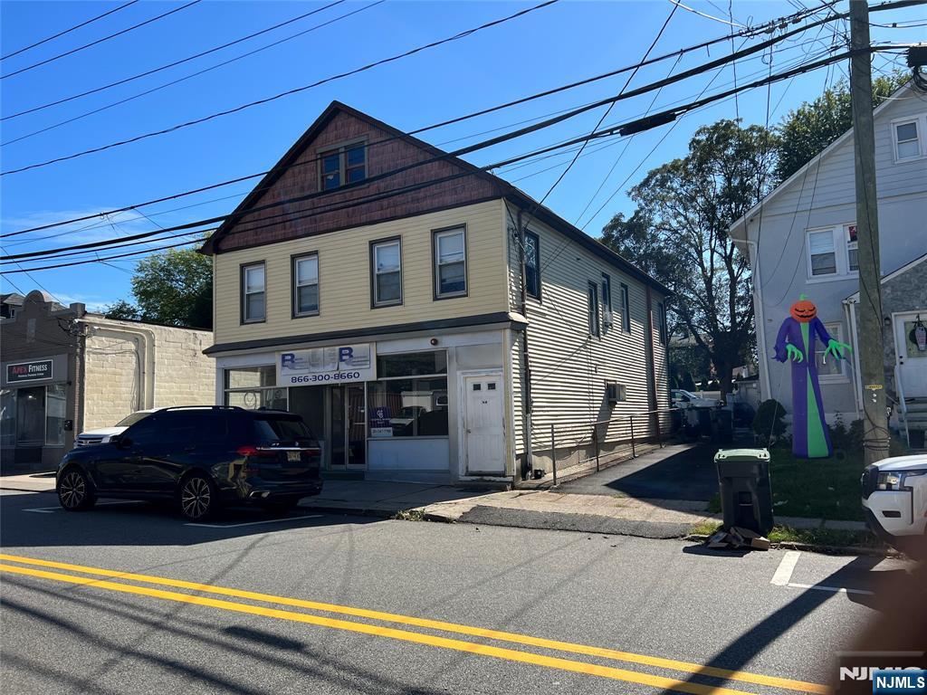 a front view of a house with cars parked on road