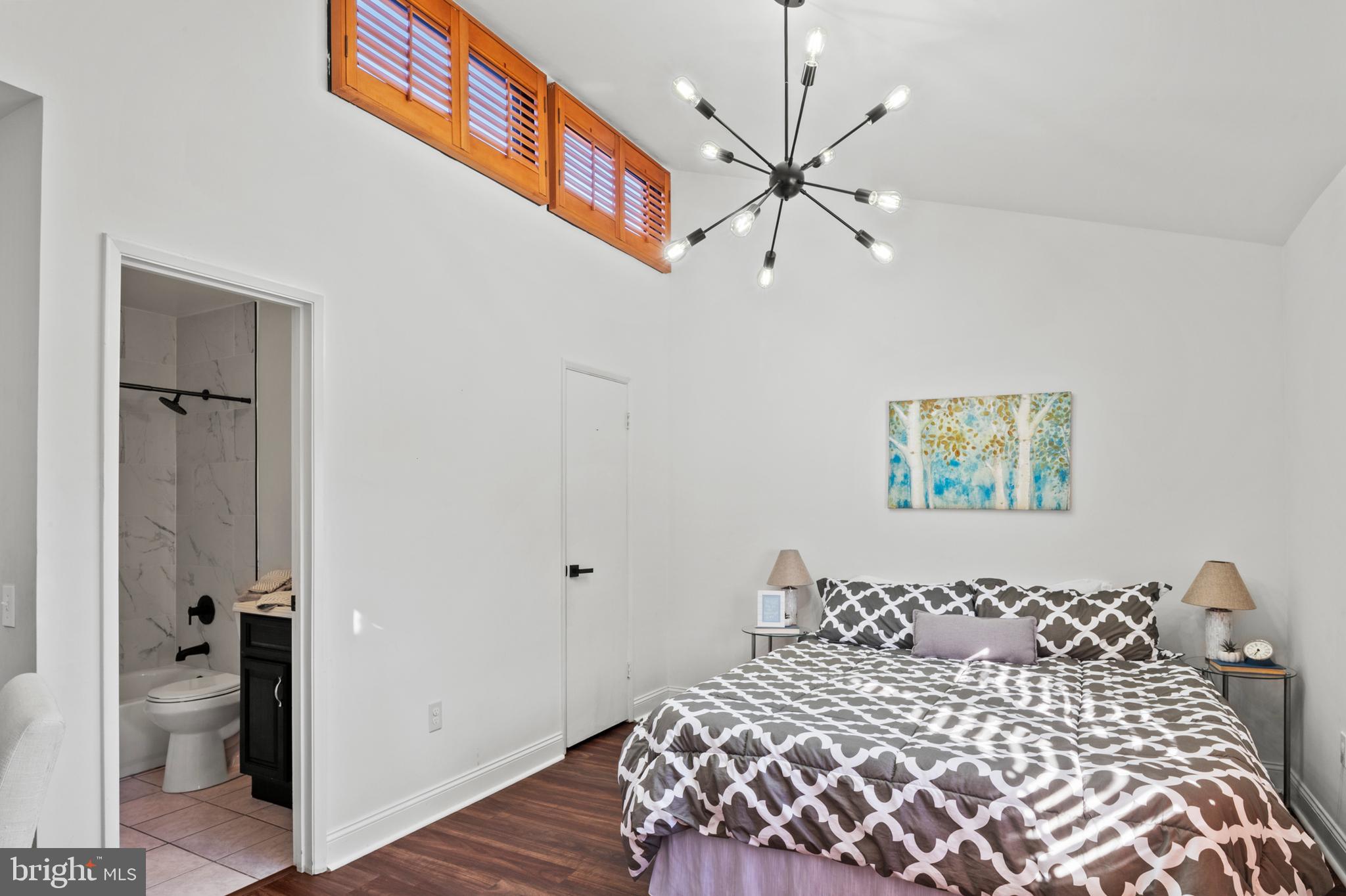 11246 Snowflake Court, Unit A121 Columbia, MD 21044 - Photo 16 of 36 a bedroom with a large bed and a chandelier