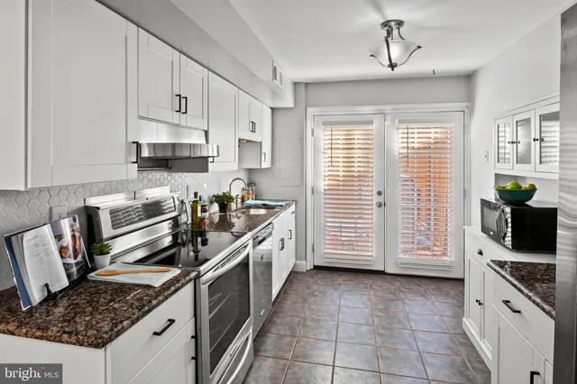 a kitchen with granite countertop white cabinets and stainless steel appliances
