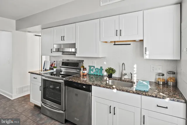 a kitchen with stainless steel appliances white cabinets and a stove top oven