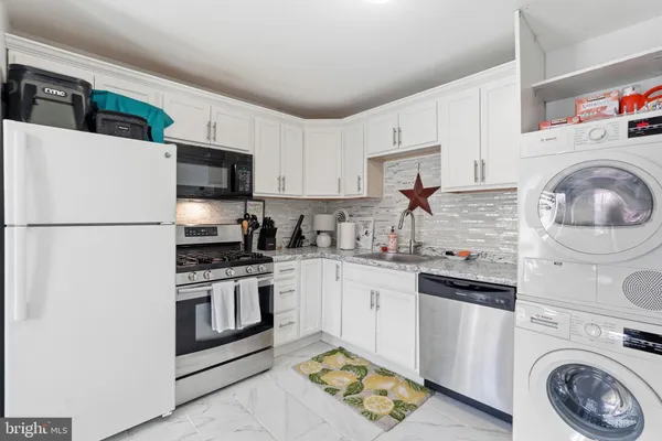 a kitchen with stainless steel appliances granite countertop a sink a stove a refrigerator and cabinets