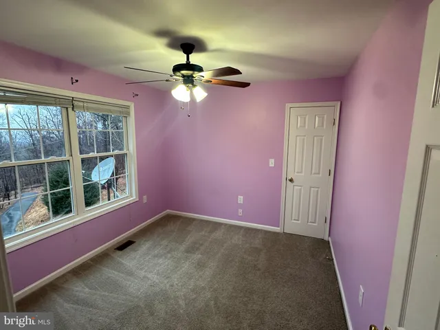 an empty room with a ceiling fan and a window